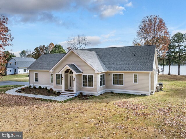 view of front of home with a front yard, a water view, and central air condition unit