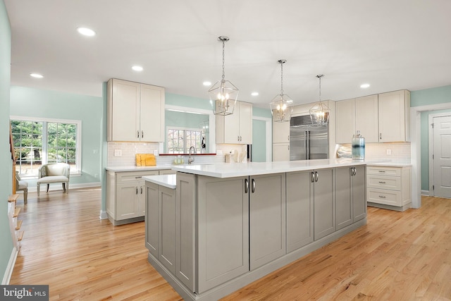 kitchen with gray cabinetry, built in refrigerator, and plenty of natural light