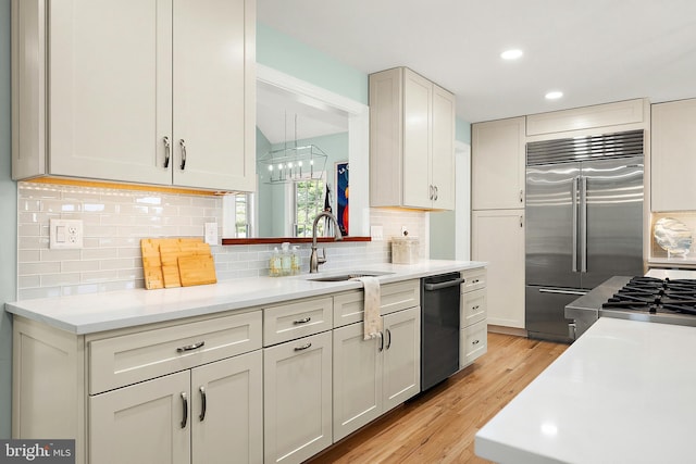 kitchen with stainless steel built in refrigerator, decorative backsplash, light wood-type flooring, and sink