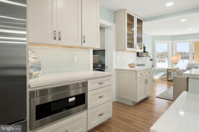 kitchen featuring white cabinets, wood-type flooring, backsplash, and stainless steel appliances