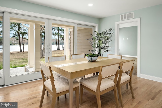 dining area featuring light hardwood / wood-style floors and a water view