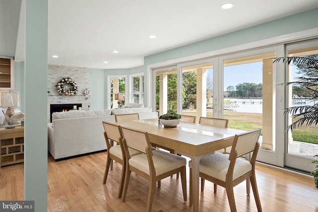 dining space with light hardwood / wood-style floors, a brick fireplace, and plenty of natural light