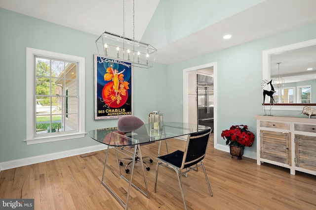 dining space featuring hardwood / wood-style flooring, a notable chandelier, and vaulted ceiling