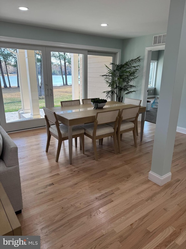 dining space with plenty of natural light, a water view, and light wood-type flooring