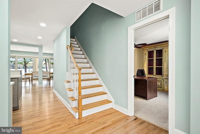 staircase featuring ceiling fan and hardwood / wood-style floors