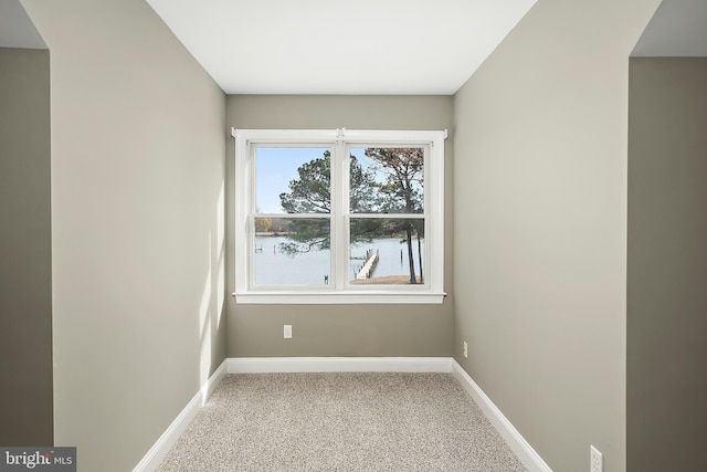 carpeted spare room featuring a water view