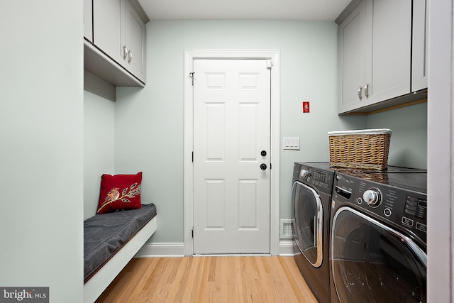 laundry room with independent washer and dryer, cabinets, and light wood-type flooring