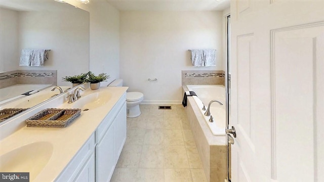 bathroom featuring tile patterned floors, tiled bath, vanity, and toilet