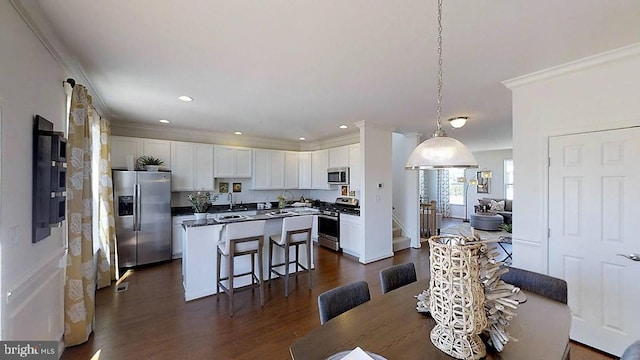 dining area with sink, ornamental molding, and dark wood-type flooring