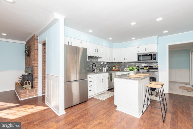 kitchen featuring stainless steel appliances, dark wood-type flooring, white cabinetry, a kitchen island, and a breakfast bar area