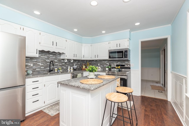 kitchen with dark hardwood / wood-style floors, a center island, white cabinetry, and stainless steel appliances