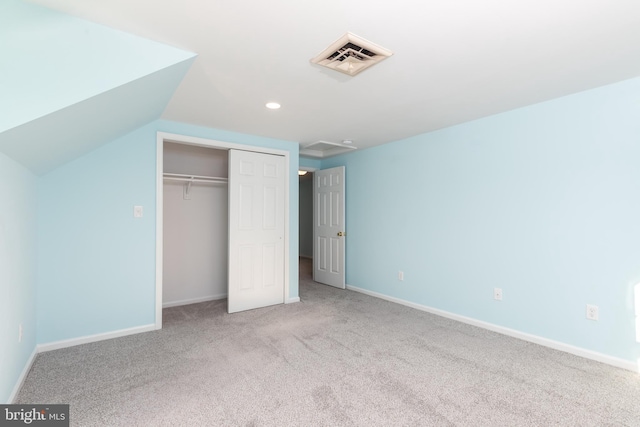 unfurnished bedroom with light colored carpet, vaulted ceiling, and a closet