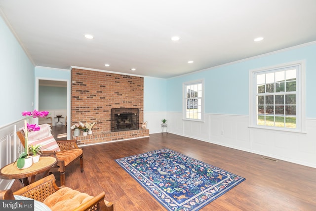 living room with ornamental molding, dark wood-type flooring, and a brick fireplace