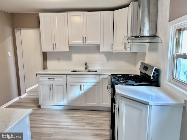 kitchen with white cabinetry, sink, tasteful backsplash, gas range oven, and light hardwood / wood-style floors