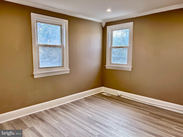 spare room featuring light wood-type flooring, crown molding, and a wealth of natural light