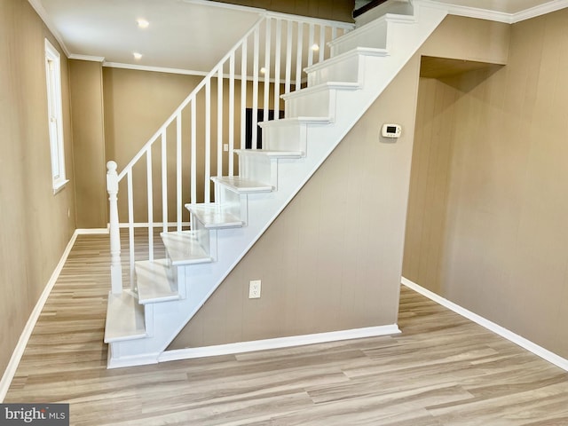 stairway featuring ornamental molding and hardwood / wood-style flooring