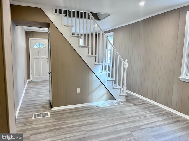 stairs with hardwood / wood-style floors, crown molding, and wooden walls