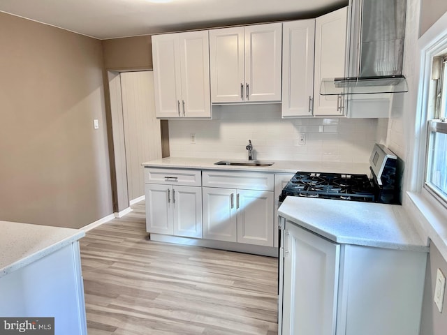 kitchen with tasteful backsplash, sink, white cabinets, and light wood-type flooring