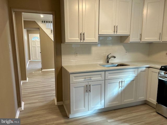 kitchen featuring white cabinets, light hardwood / wood-style floors, and tasteful backsplash