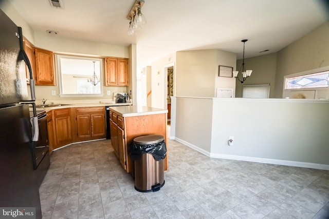 kitchen with sink, black appliances, pendant lighting, a notable chandelier, and a kitchen island