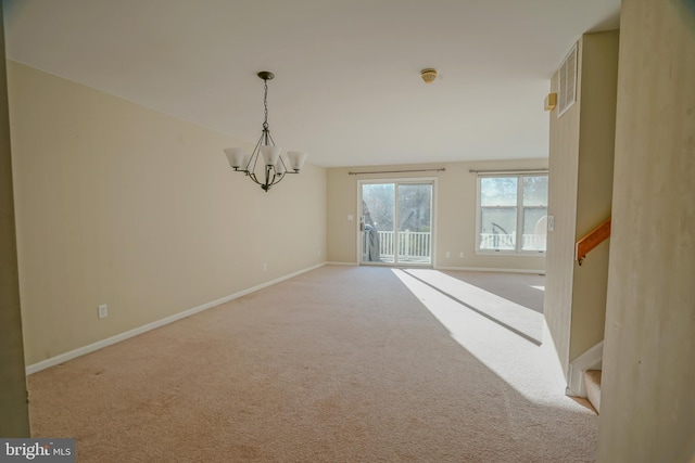 carpeted empty room with a notable chandelier