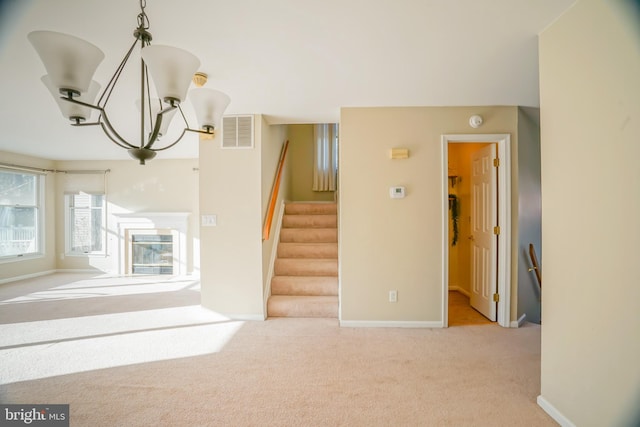 unfurnished living room featuring a notable chandelier and light carpet