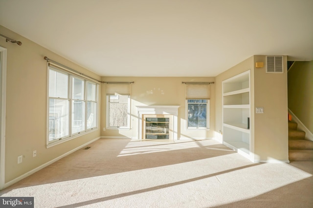 unfurnished living room featuring built in features and carpet floors