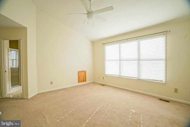 empty room with plenty of natural light, ceiling fan, light colored carpet, and lofted ceiling