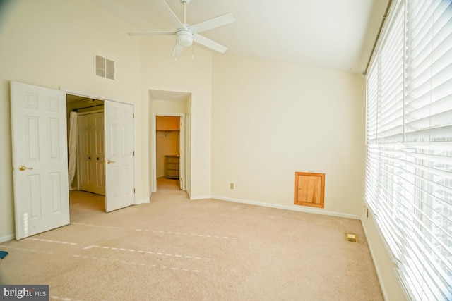 unfurnished bedroom featuring light colored carpet, high vaulted ceiling, and a closet