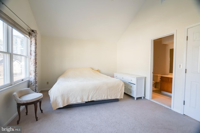 bedroom with high vaulted ceiling, light colored carpet, connected bathroom, and multiple windows