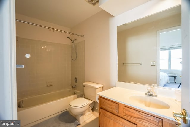 full bathroom featuring vanity, tiled shower / bath combo, and toilet