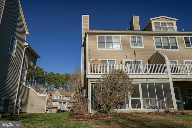 rear view of property with a sunroom and a yard