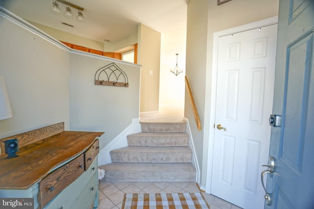 stairs featuring tile patterned flooring and a chandelier