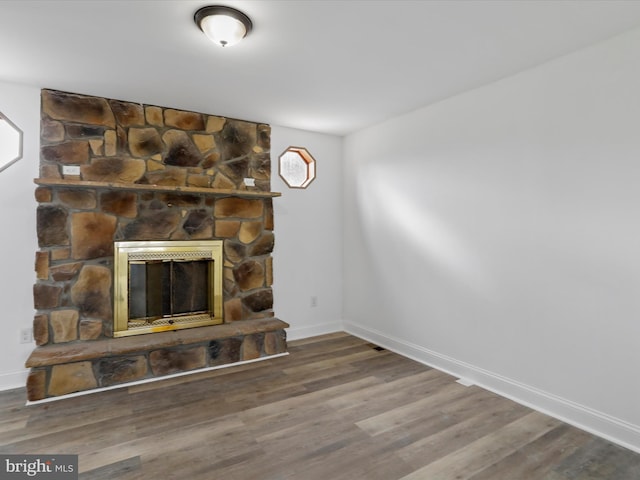 unfurnished living room with a stone fireplace and hardwood / wood-style floors