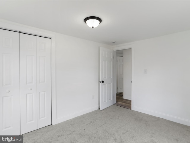 unfurnished bedroom with light colored carpet and a closet