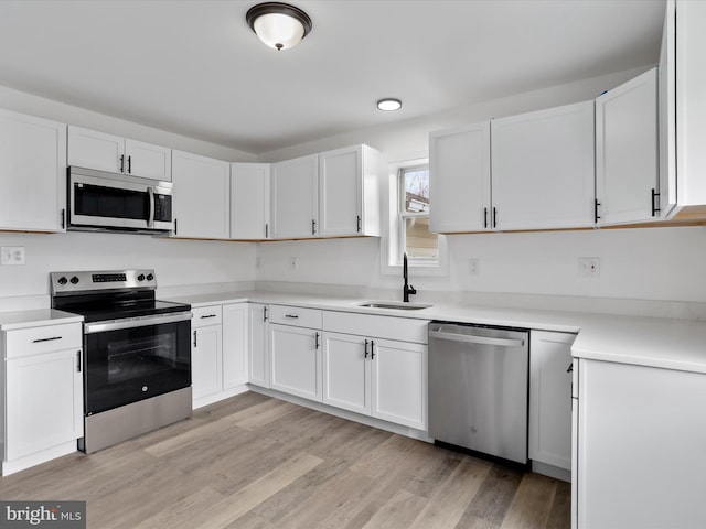 kitchen with white cabinets, stainless steel appliances, light hardwood / wood-style floors, and sink