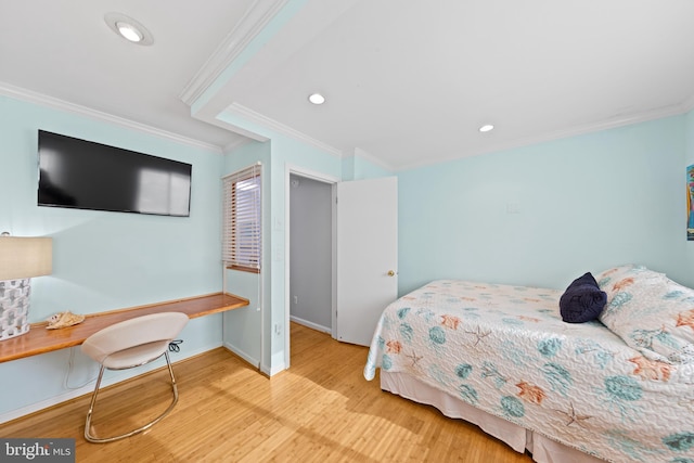 bedroom featuring built in desk, light hardwood / wood-style flooring, and crown molding