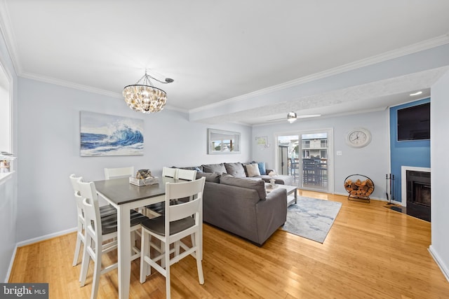 dining space featuring light hardwood / wood-style floors, ceiling fan with notable chandelier, and ornamental molding