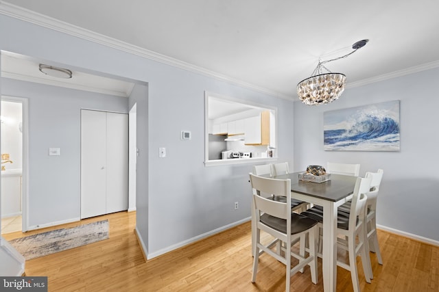 dining area featuring a notable chandelier, crown molding, and light hardwood / wood-style flooring