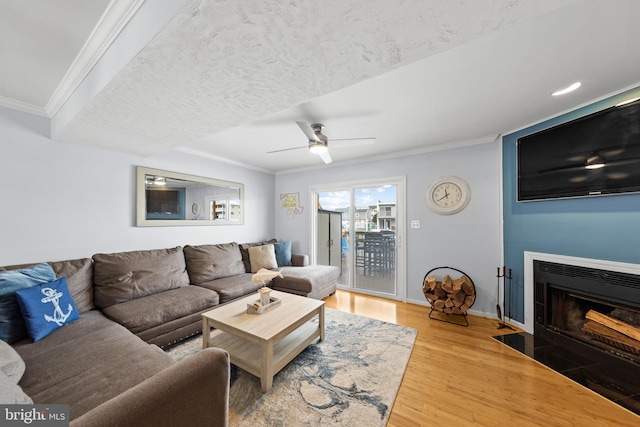 living room with crown molding, ceiling fan, and wood-type flooring