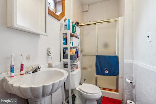 bathroom featuring tile walls, toilet, walk in shower, and sink