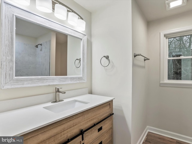 bathroom with hardwood / wood-style floors, vanity, and tiled shower