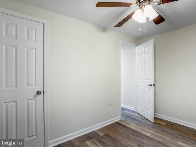 unfurnished bedroom with ceiling fan and dark wood-type flooring