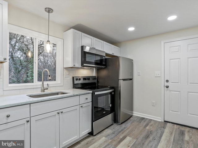 kitchen with white cabinetry, sink, appliances with stainless steel finishes, and light hardwood / wood-style flooring