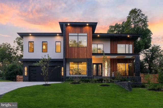 back house at dusk with a lawn and a garage