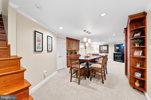 carpeted dining area featuring crown molding and a fireplace