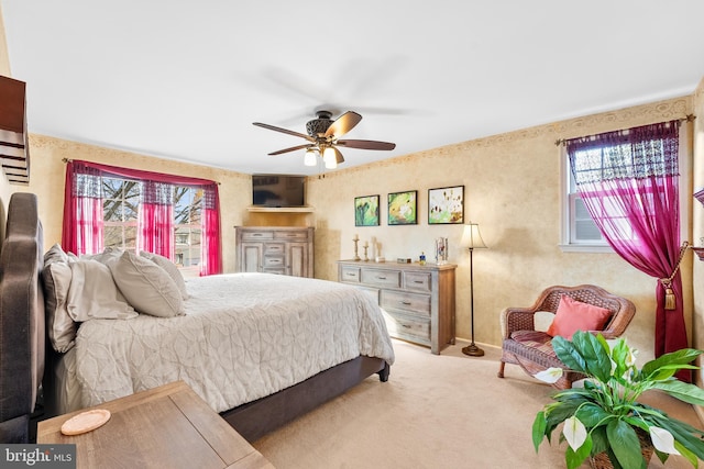 bedroom featuring multiple windows, ceiling fan, and light colored carpet