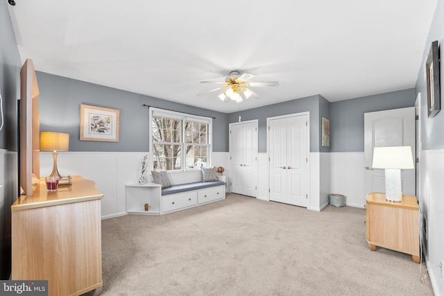 carpeted bedroom featuring ceiling fan and two closets