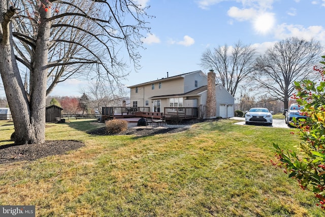 rear view of house with a garage, a deck, and a yard