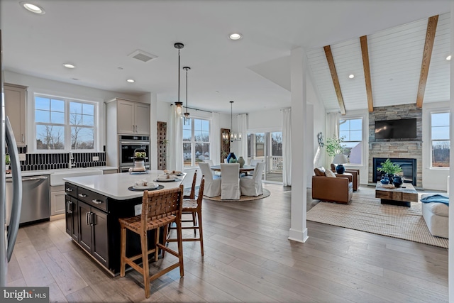 kitchen featuring vaulted ceiling with beams, a wealth of natural light, a center island, and a fireplace